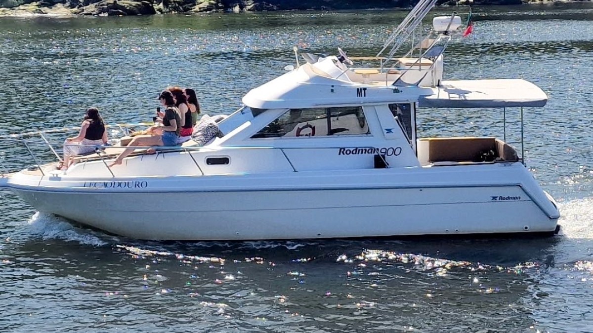 People relaxing on a white boat named Rodman 900 on water.