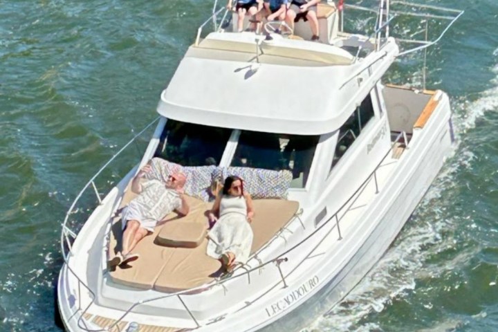 People relaxing on a white boat cruising in the water.