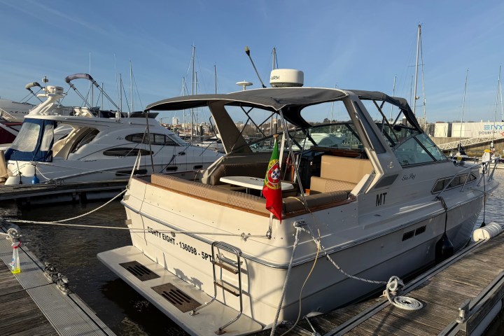 Motorboat docked at marina with flag at back and clear skies.