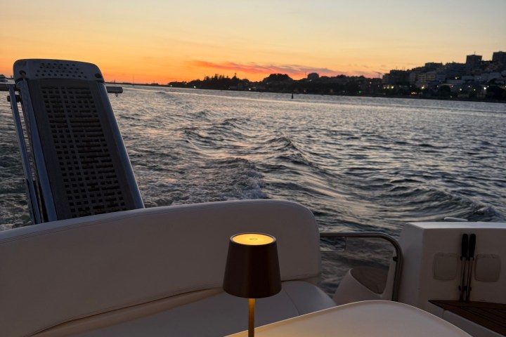 Sunset over water viewed from boat with lit table lamp.